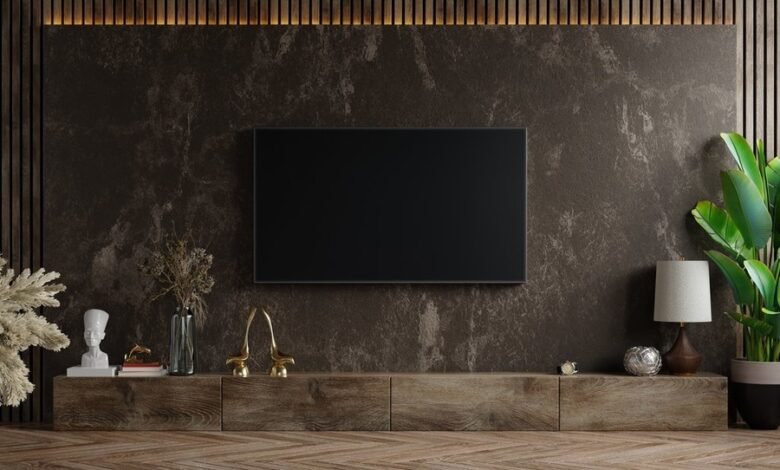 Mockup a TV wall mounted in a dark room with plant on dark marble wall background,3d rendering